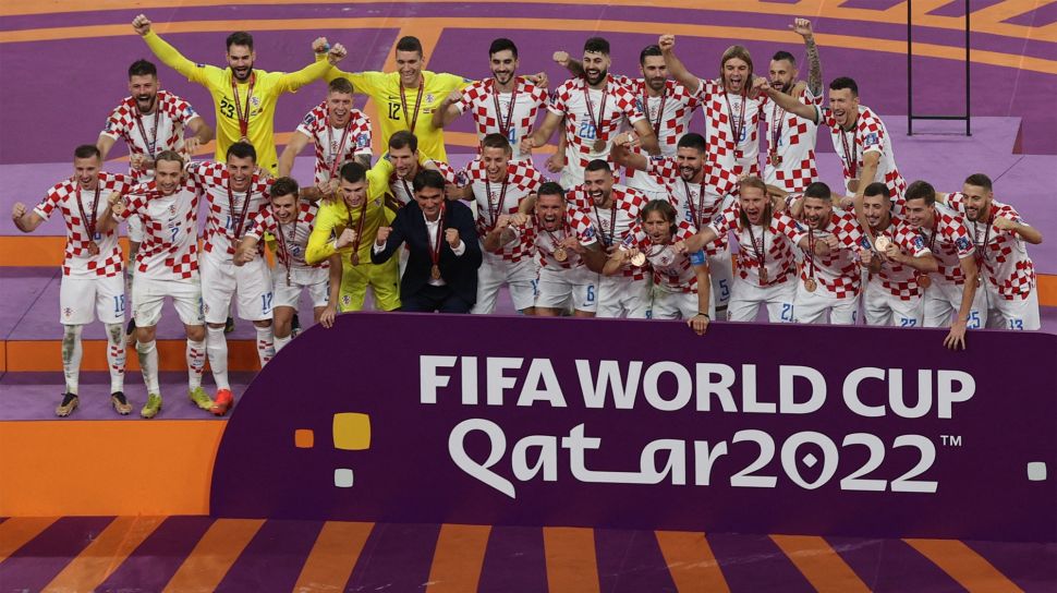 Para pemain Kroasia merayakan dengan medali setelah memenangkan pertandingan play-off perebutan tempat ketiga Piala Dunia 2022 antara Kroasia dan Maroko di Stadion Internasional Khalifa di Doha, Qatar, Sabtu (17/12/2022). [ADRIAN DENNIS / AFP]