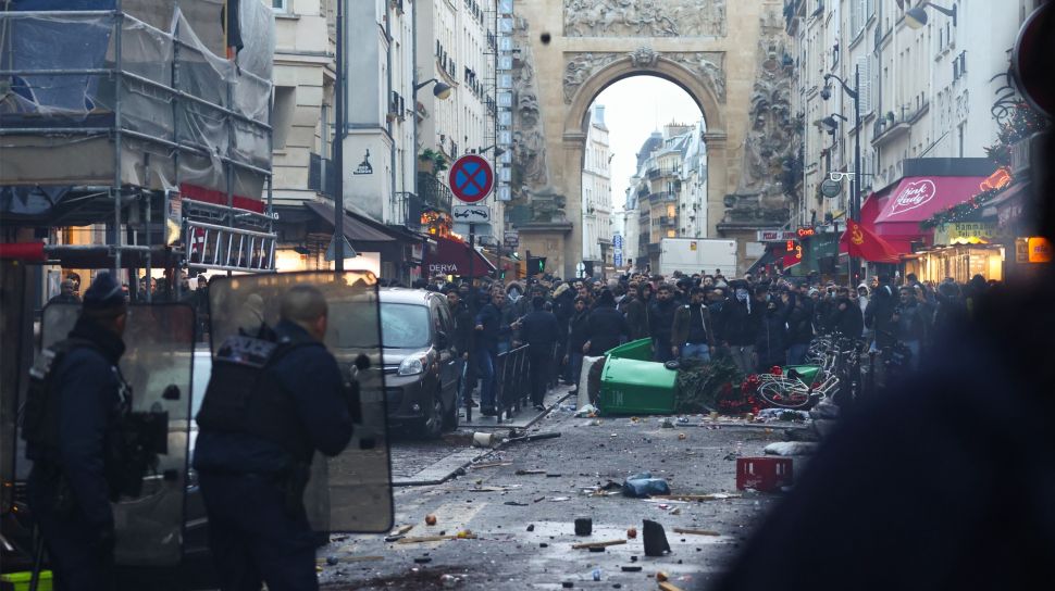 Para pengunjuk rasa bentrok dengan petugas polisi anti huru hara Prancis menyusul insiden penembakan kepada komunitas Suku Kurdi di Paris, Prancis, Jumat (23/12/2022). [Thomas SAMSON / AFP]