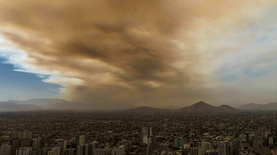 Pemandangan kota yang diselimuti asap dari kebakaran hutan yang melanda daerah sekitarnya di Santiago, Chili, Jumat (16/12/2022). [JAVIER TORRES / AFP]